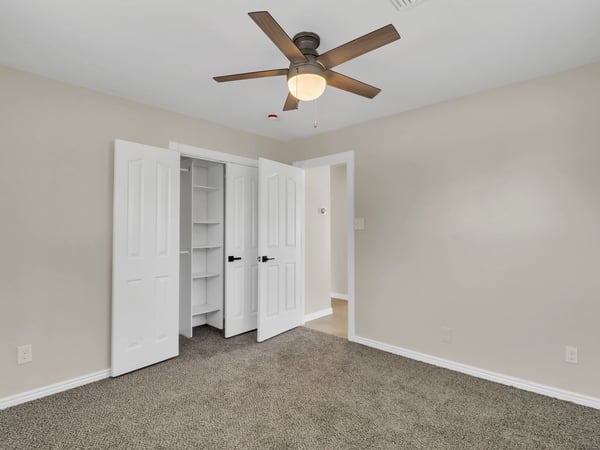 Well-sized bedroom featuring soft carpeting, ceiling fan, built-in closet organization, and clean neutral finishes. This comfortable space completes the updated interior of this Phoenix rental.