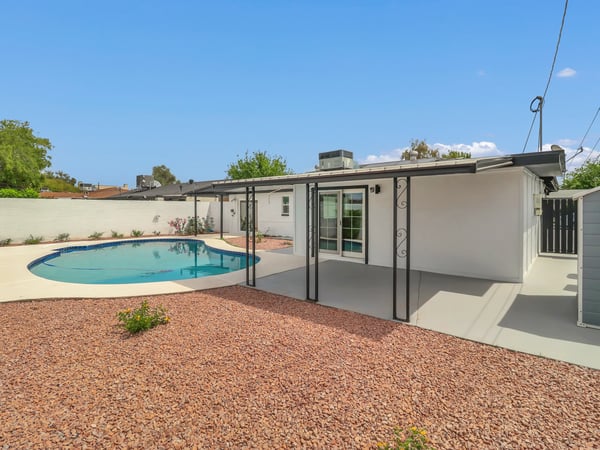 Beautiful backyard featuring a covered patio, sparkling swimming pool, fresh landscaping, and generous outdoor living space. This updated Phoenix rental offers the perfect setting for relaxing or hosting friends and family.