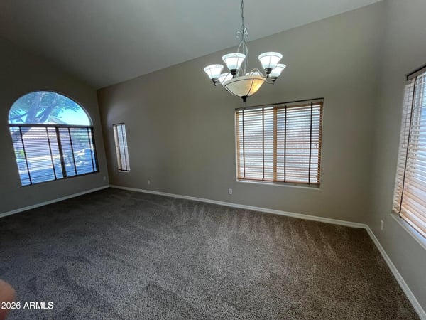 The expansive formal living area features dramatic vaulted ceilings, oversized picture windows, plush carpeting, and flexible space perfect for entertaining or everyday living.