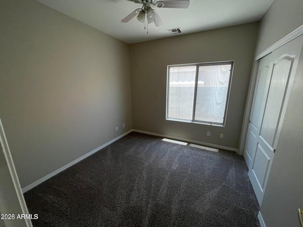 Featuring soft carpeting, a ceiling fan, natural light, and a spacious closet, this versatile bedroom easily accommodates guests, family, or a dedicated workspace.