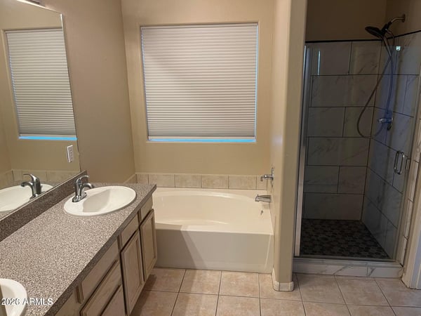 The spacious primary bath offers dual vanities, a soaking tub, an updated walk-in shower, and plenty of natural light, creating a comfortable retreat after a long day.