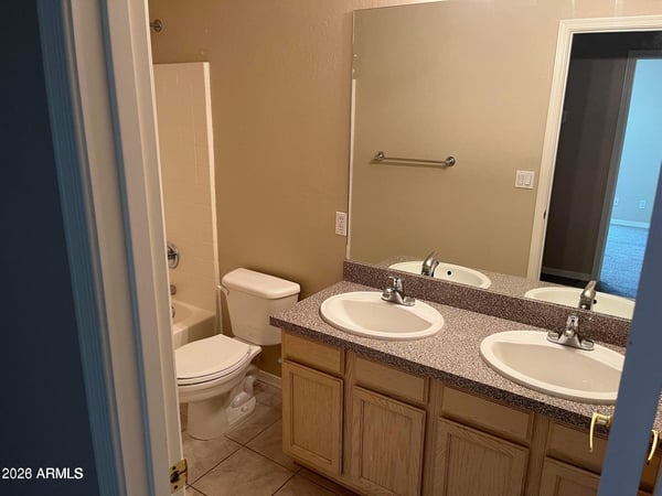 A dual-sink vanity, tile flooring, and a full tub and shower combination make this well-appointed bathroom ideal for everyday comfort and convenience.