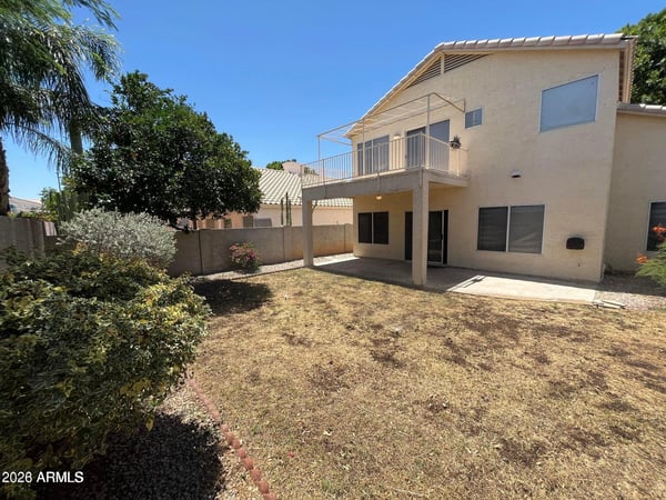 Relax or entertain in the private backyard featuring a covered patio, elevated balcony, mature landscaping, and plenty of outdoor space to enjoy Arizona living in Gilbert.