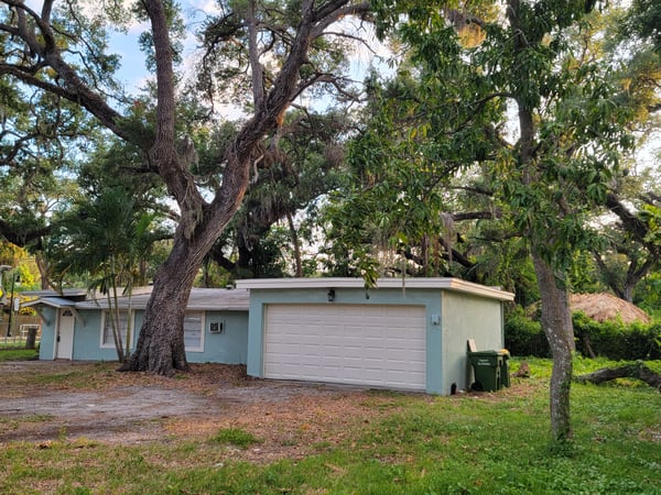 Cozy home surrounded by mature trees, offering potential for outdoor living and personal touches.