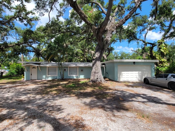This spacious home features a large lot, abundant trees, and a driveway for ample parking.