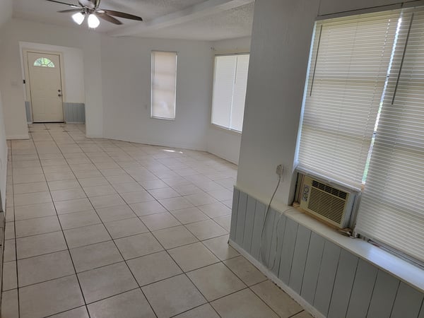Spacious, well-lit living area featuring tile flooring and large windows for natural light.
