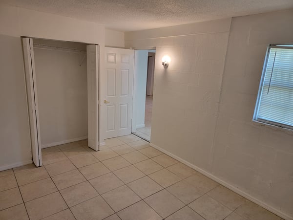 Spacious room featuring tiled floors, natural light, and nearby closet for ample storage convenience.