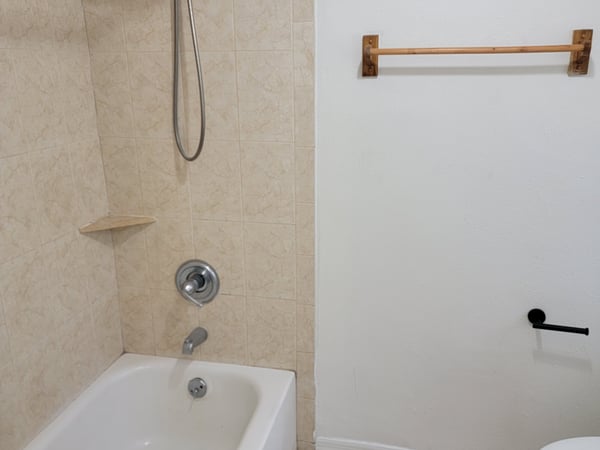 Modern bathroom featuring a tub and shower combination, complemented by clean tile and minimalist fixtures.