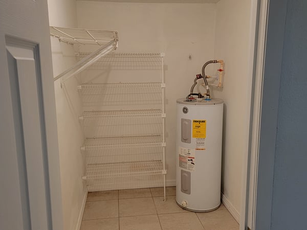 Spacious utility room featuring ample shelving and a water heater, perfect for organized storage solutions.