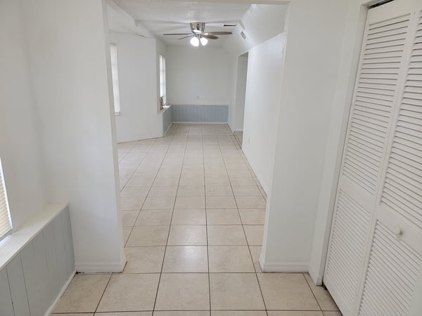 Spacious open-layout living area featuring tiled floors and ample natural light, perfect for versatile living.