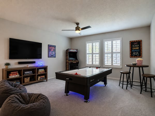 This entertainment space features an air hockey table, retro arcade game, and cozy seating for relaxation.