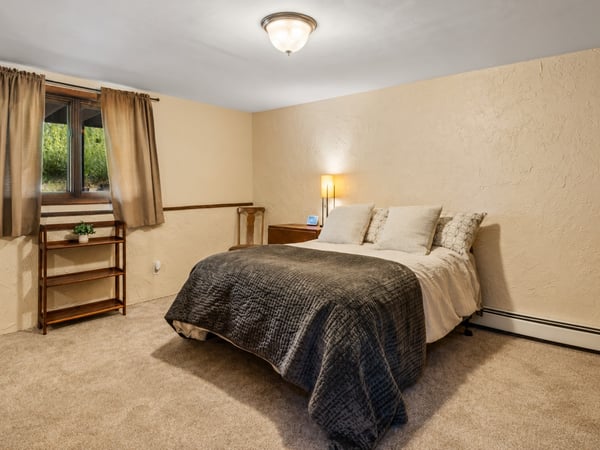 Cozy bedroom featuring natural light, soft carpeting, and modern furnishings for a comfortable retreat.