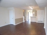Spacious open layout with warm wood flooring, featuring a seamless flow between living and dining areas.
