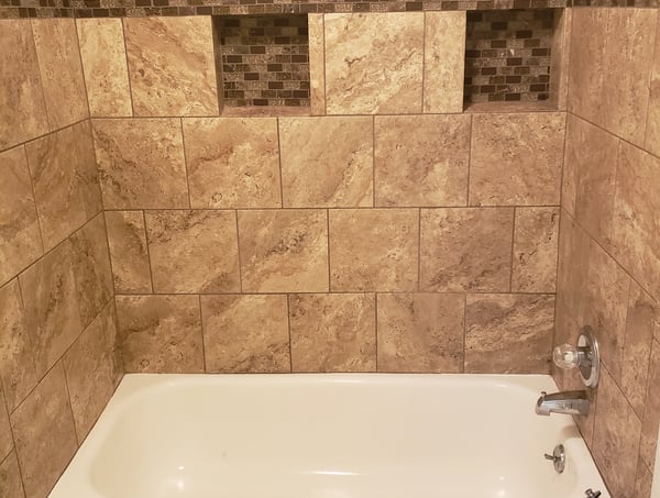 Modern bathroom featuring a textured tile design, built-in niches, and a sleek bathtub for comfort.