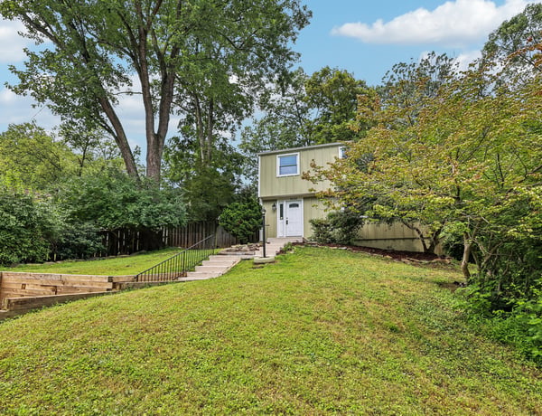 This two-story home features a spacious yard, mature trees, and a welcoming entrance.