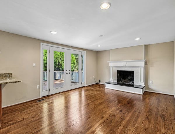 Bright, open living space featuring large windows, hardwood floors, and a cozy fireplace for gatherings.