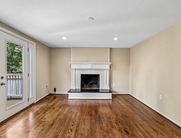Bright and inviting living area features a cozy fireplace, large windows, and rich hardwood flooring.