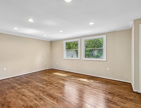 Spacious, well-lit room with hardwood floors and ample natural light from large windows.