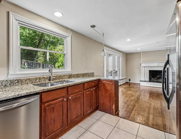 Bright kitchen with ample counter space, flowing into a cozy living area with a fireplace.