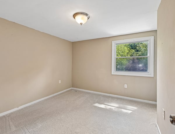 Spacious bedroom with natural light, featuring a window and versatile space for personalized design.
