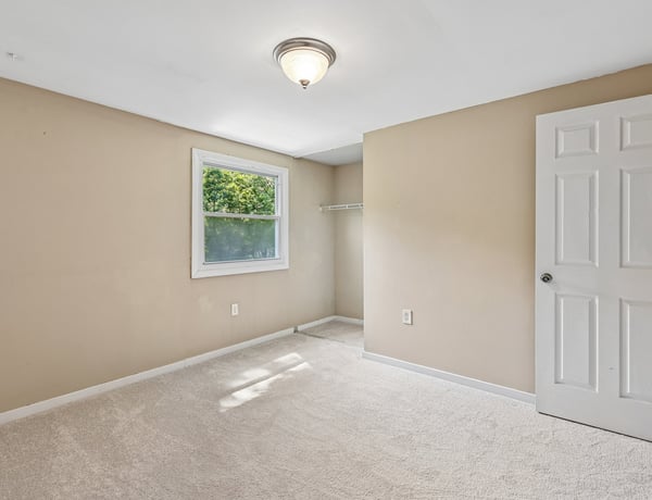 This versatile bedroom features neutral tones, natural light, and ample space for personal design.