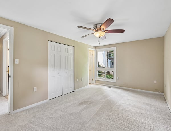 Spacious bedroom featuring a ceiling fan, natural light, and convenient access to a private balcony.