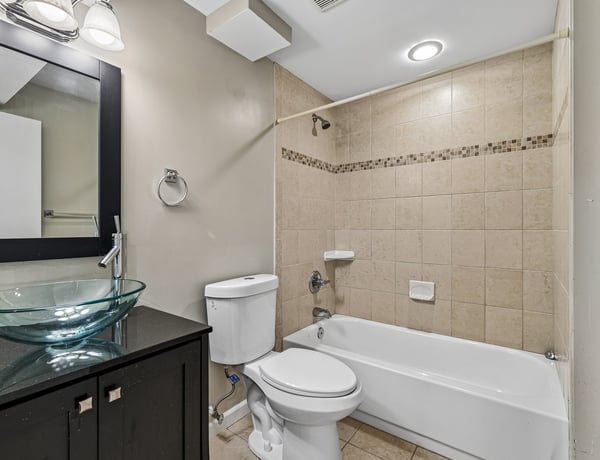 Modern bathroom featuring a sleek design, glass vessel sink, and convenient tub-shower combination.