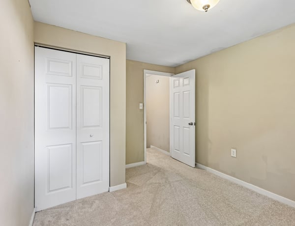 Spacious bedroom featuring ample closet space and fresh carpeting, perfect for personalized decor and comfort.