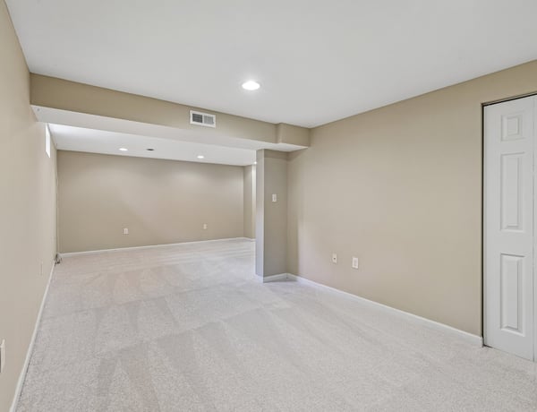 Spacious, versatile basement area ready for customization, featuring neutral tones and ample natural light.