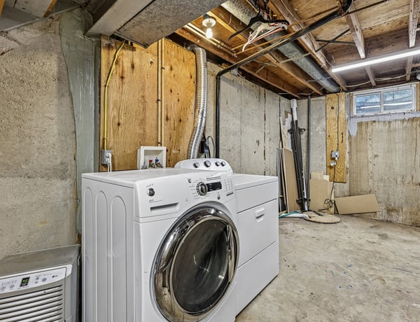 Spacious basement laundry area featuring modern washer and ample storage potential for future projects.