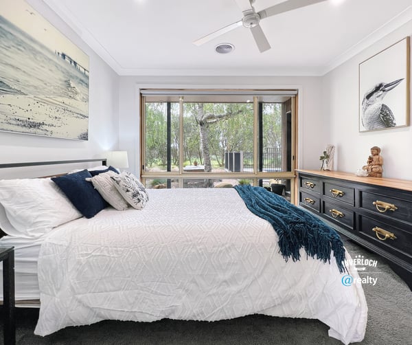 Spacious bedroom featuring large windows, natural light, and a view of lush outdoor greenery.