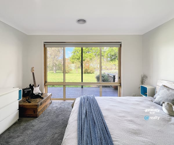Bright bedroom featuring a large window with garden views, complemented by modern furnishings and cozy atmosphere.