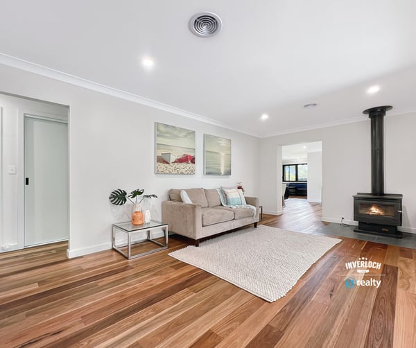 Spacious living area featuring hardwood floors and a cozy wood-burning stove, perfect for gatherings and relaxation.
