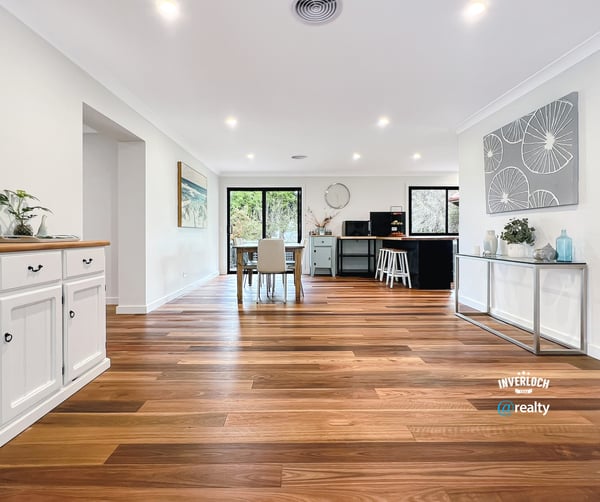 Spacious open-concept living area with warm wooden floors and abundant natural light, ideal for entertaining.