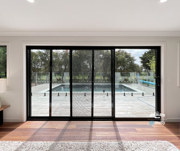 Bright and inviting living space with expansive glass doors opening to a private pool and outdoor deck.