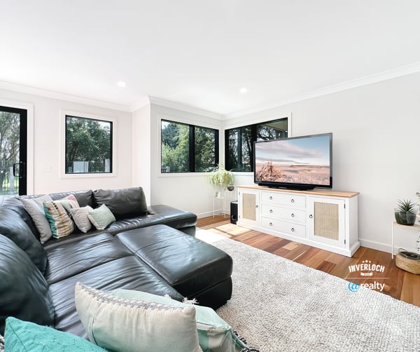 Spacious living area features large windows, modern furnishings, and ample natural light for a welcoming atmosphere.