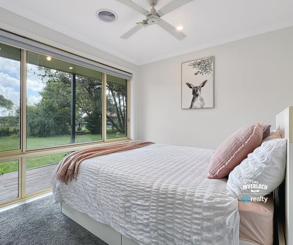 Bright and airy bedroom with large windows offering stunning views of the lush backyard.