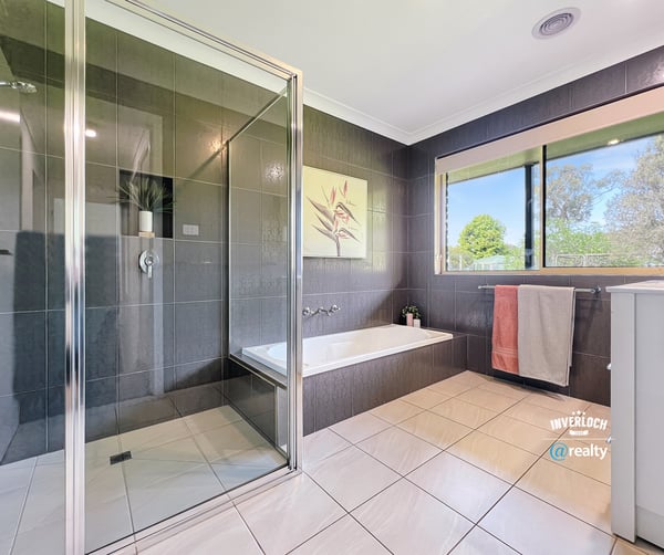 Modern bathroom featuring sleek tiles, a spacious shower, and large windows for natural light.