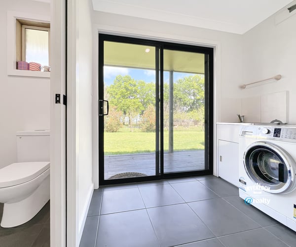 Bright laundry room featuring a washing machine, ample storage, and direct access to the outdoor space.