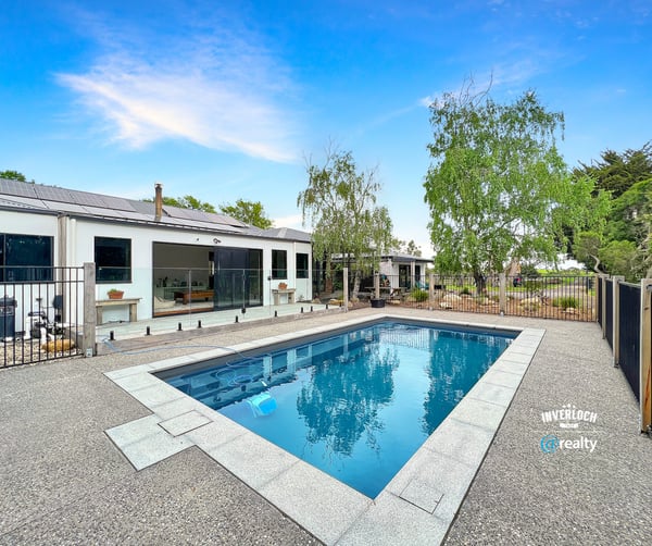 This contemporary home features a spacious outdoor area with a pristine pool and landscaped surroundings.
