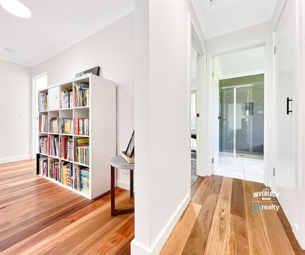 Bright and inviting interior featuring wooden floors, a spacious hallway, and a versatile bookshelf area.