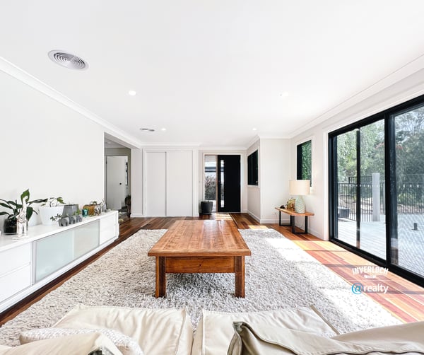 Bright open living space featuring large windows, natural light, and a warm wood coffee table.