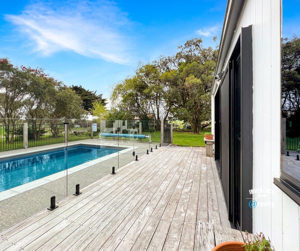 Discover a modern retreat featuring a spacious deck and inviting pool surrounded by lush greenery.