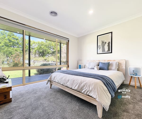 Bright and airy bedroom featuring large windows that invite natural light and offer picturesque garden views.