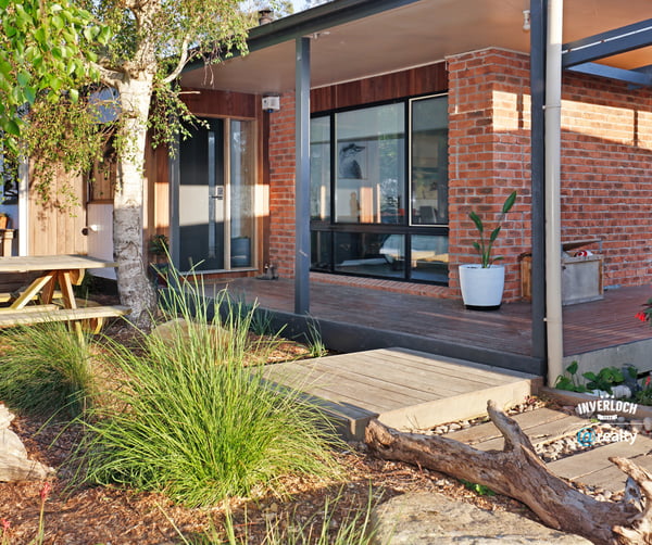 Contemporary home featuring expansive windows and an inviting outdoor space surrounded by lush greenery.