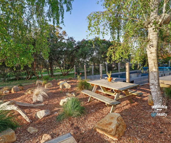 This outdoor space features a picnic area surrounded by native landscaping and a pool in the background.