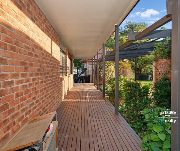 Inviting walkway lined with brick and greenery, leading to a secluded outdoor living space.