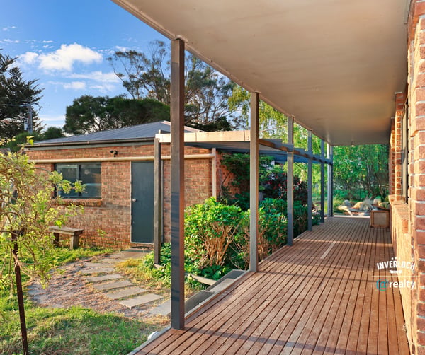 Spacious covered porch leads to a well-maintained garden, offering a welcoming entry to this unique property.