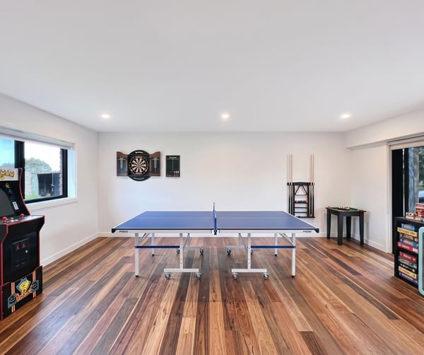 Bright recreational space featuring a ping pong table, arcade machine, and dartboard for entertainment.