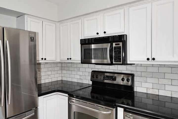 11 of 29. Contemporary kitchen showcasing stainless steel appliances, white cabinetry, subway tile accents, and updated finishes. Designed for both efficiency and style, this kitchen is ready for everyday living.